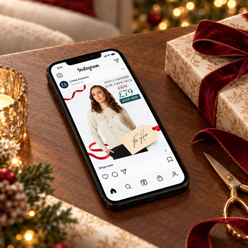 Linea Azzurro Instagram ad for a cashmere ecru crew neck on a phone beside Christmas gift wrap