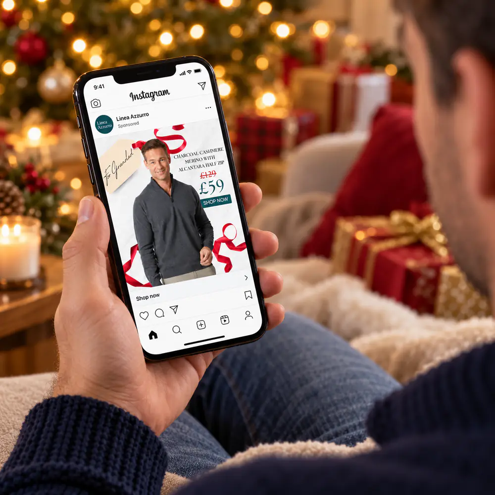 Man browsing a Linea Azzurro half zip ad on his phone by the Christmas tree