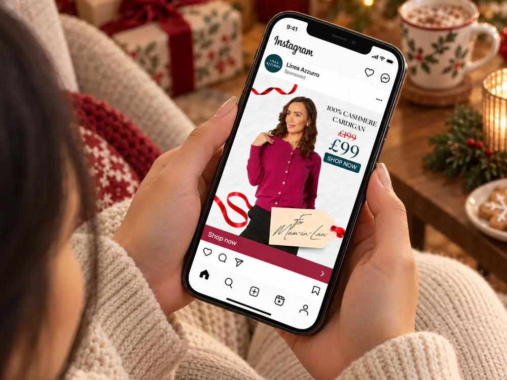 Woman browsing a Linea Azzurro cashmere cardigan ad on her phone at Christmas